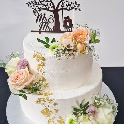 Zweistöckige Hochzeitstorte mit weißer Creme und Blattgold und passenden Hochzeitsblumen