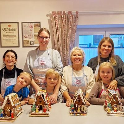 Eltern dekorieren mit ihren Kindern Lebkuchenhäuser