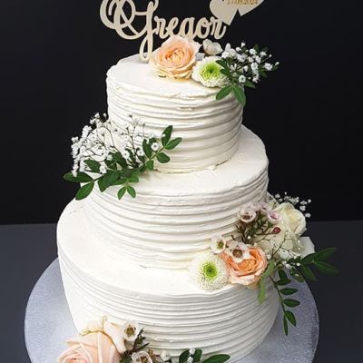 Dreistöckige Hochzeitstorte mit weißer Creme und Blumen