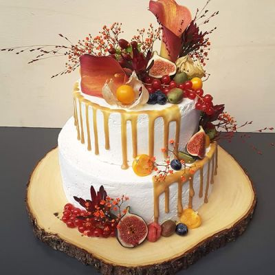 Zweistöckige weisse Torte mit Creme, Früchten und Blumen