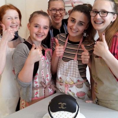 Teenies beim Backkurs beim Dekorieren einer Handtaschentorte