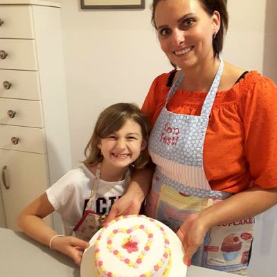 Mutter und Tochter dekorieren eine Torte mit Blumen in Herzform