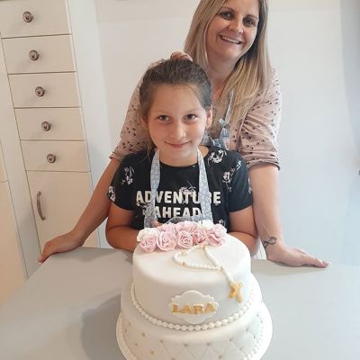 Mutter und Tochter backen und dekorieren Tauftorte mit Fondant