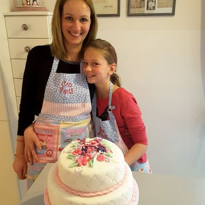 Tochter und Mutter dekorieren und backen zweistöckige Torte mit Fondant und Blumen