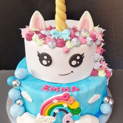 Zweistöckige Geburtstagstorte mit einer Einhorndekoration und einem Regenbogen